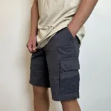 Bermuda cargo gris oscuro de gabardina, con bolsillos laterales y traseros con solapa.