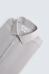 Camisa de manga larga para hombre, color gris claro con micro-estampado de cuadros sutiles. Presenta cuello italiano y cierre frontal de botonadura.