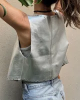 Chaleco corto plateado de cuero ovino con tachas metálicas en el cuello y el ruedo.