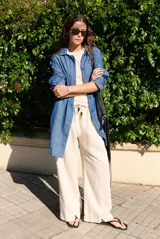 Pantalón de lino color beige, de corte ancho y relajado, con cintura elástica ajustable mediante cordón con detalles decorativos.
