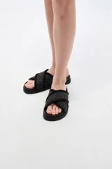 Sandalias planas color crudo con tiras cruzadas de tejido textil con diseño geométrico y detalles de flecos en los bordes.