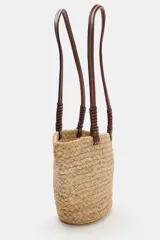 Bolso tipo shopper formato mini confeccionado en yute trenzado, con doble asa de mano en cuero sintético color marrón.