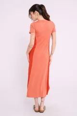 Vestido midi de corte recto y diseño bicolor, con frente en color crema y laterales en color beige. Presenta cuello redondo, mangas cortas y aberturas laterales en el ruedo.