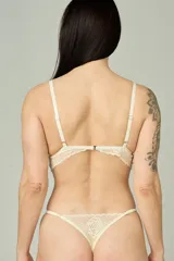 Conjunto de lencería compuesto por un bralette triangular de encaje floral y una bombacha tipo tanga a juego con detalles de encaje y tiras ajustables.
