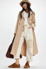 Tapado largo de tejido de punto color beige con diseño a cuadros sutil. Presenta cuello solapa, cierre frontal con botones y bolsillos laterales.