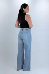 Pantalón wide leg de denim celeste claro, con costuras deflecadas y detalles deshilachados en la cintura y el remate de las piernas.