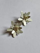 Par de aros dorados con forma de flor, con pétalos texturizados y centro de cuentas pequeñas.