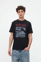 Remera negra de algodón pesado con calce relaxed, cuello redondo y manga corta. Cuenta con un diseño gráfico central que combina fotografía de un cactus en tonos grises con la leyenda "Wilder Days" en granate.
