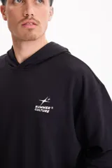 Buzo canguro oversize negro sin friza, con capucha, bolsillo delantero tipo canguro y pequeño estampado blanco en el pecho con la inscripción "Summer Culture".