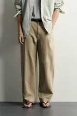 Pantalón relaxed fit de color beige, confeccionado en tejido con mezcla de algodón y lino, con diseño de cinco bolsillos, efecto lavado y cierre frontal con cremallera y botón.