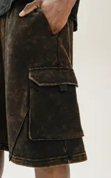 Bermuda cargo de algodón rústico, color marrón oscuro con efecto desgastado (acid wash/oxidado). Presenta un calce oversize, cintura elástica y grandes bolsillos laterales con tapa.