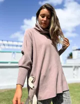 Polerón de cuello alto y corte oversize, color rosado, con mangas largas de puño acanalado y detalle de ojalillos metálicos con tiras en los laterales.