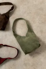 Mini cartera tipo tote de cuero agamuzado, con asa ancha de hombro, cierre con botón de imán y bolsillo interior.