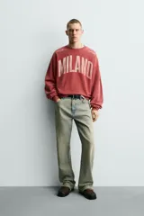 Sudadera de corte boxy fit con cuello redondo y manga larga. Presenta un diseño con efecto lavado y estampado frontal con la palabra Milano en tipografía universitaria a contraste.