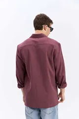 Camisa rústica de manga larga color gris oscuro, con cuello clásico, cierre frontal con botones y un bolsillo aplicado en el pecho.