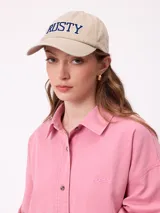 Gorro con visera de estilo clásico, confeccionado en algodón color beige, con el logo de la marca bordado en letras azules en el frente.