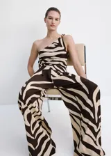 Pantalón largo de tiro medio confeccionado en viscosa fluida, con diseño recto y estampado de cebra en tonos marrón y beige. Cuenta con dos bolsillos laterales y cierre de botón.