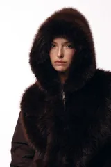 Campera de invierno con frente de piel sintética y capucha integrada, combinada con mangas acolchadas de estilo puffer en color marrón oscuro.