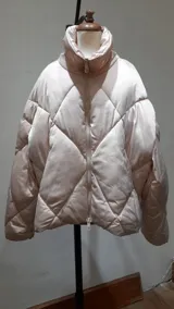 Campera puffer color beige claro con relleno, cierre frontal y cuello alto.