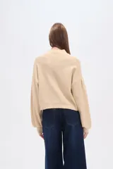 Polera de punto color marrón con destellos brillantes, cuello redondo, mangas largas abullonadas y diseño holgado.