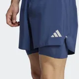Short deportivo Adidas 2 en 1 para running, confeccionado en tejido liso de poliéster reciclado. Cuenta con calzoncillo interior de malla, cintura elástica con cordón de ajuste, bolsillos laterales y detalles reflectantes.