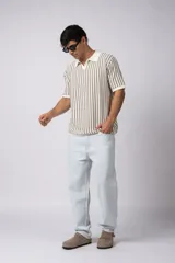 Chomba de punto con diseño de rayas verticales en color negro y blanco, cuello polo y manga corta con terminación acanalada.