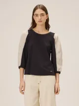 Blusa de diseño combinado con cuerpo delantero y espalda de algodón negro, y mangas abullonadas tres cuartos de lino en color beige con puños elásticos negros.