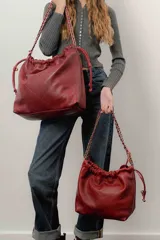 Bolso tipo shopper de cuero negro con diseño acolchado en patrón de rombos. Cuenta con cierre superior fruncido y correa de cadena metálica entrelazada con cuero.