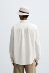 Camisa de algodón color blanco hueso, de corte regular, con cuello abotonado, manga larga terminada en puño con botón y bolsillo de parche en el pecho.