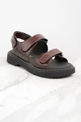 Sandalias marrones de cuero con suela de goma negra y ajuste con velcro.