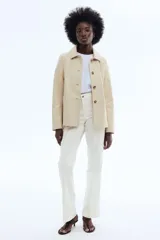 Jeans de denim blanco off-white, de tiro alto y corte acampanado con botamanga ancha y raya marcada al frente.
