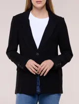 Blazer de silueta semientallada confeccionado en sastrería liviana de corte fluido, color negro, con solapa muesca clásica, cierre frontal de un solo botón, bolsillos frontales con solapa y mangas largas con puños de detalle abotonado.