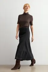 Falda larga de jean color negro, con diseño de paneles verticales y ruedo deshilachado.