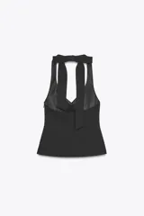 Top negro con cuello halter y escote en pico. Se ata con lazo en la espalda y tiene cierre lateral con cremallera oculta.