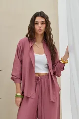 Camisa lisa color malva, de corte holgado y manga larga, con cuello camisero y cierre frontal de botones.