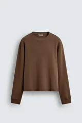 Sudadera de corte boxy fit, color marrón, con cuello redondo y manga larga. Presenta acabados en rib en puños y ruedo.