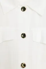 Blusa negra de cuello solapa y manga corta, con bolsillos con solapa en el pecho, bajo elástico y cierre frontal con botones.