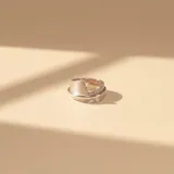 Anillo de plata con acabado satinado, diseño envolvente con una banda ancha que se cruza sobre sí misma.