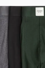 Pack de tres calzoncillos tipo trunk (boxer ajustado a media pierna) con cintura elástica. Incluye uno verde oscuro, uno gris jaspeado y uno negro.