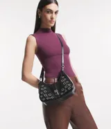 Bolso baguette Satinato de PU color negro, decorado con múltiples ojales metálicos plateados y remaches. Cuenta con un cierre de solapa frontal con hebilla metálica y correa para el hombro.