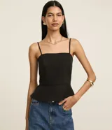 Blusa de sastrería confeccionada en twill negro, con volado peplum en el bajo, escote cuadrado y tirantes finos.