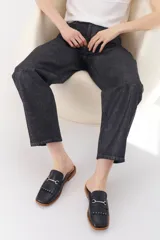 Mocasín abierto de cuero color crema con detalle de hebilla metálica plateada y flecos en el empeine.