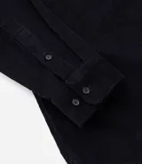 Camisa de hombre color verde oscuro, confeccionada en terciopelo, con cuello clásico, manga larga y dos bolsillos frontales con solapa y botón. Cierre frontal con botones.