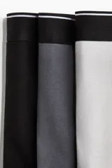 Pack de tres calzoncillos tipo trunk de punto elástico de algodón en gris y negro, con cintura elástica con logo en blanco y costuras planas. Confeccionados con tecnología Lycra® Xtra Life™.