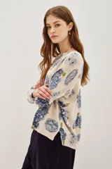 Sweater de punto con diseño estampado de flores en tonos azules y verdes sobre base color crema. Presenta cuello redondo y mangas largas con corte holgado.