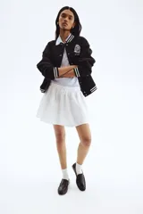 Campera de béisbol negra con cuello, puños y bajo acanalados con rayas blancas. Presenta un escudo bordado en blanco en el pecho.