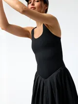 Vestido corto deportivo negro con falda plisada y short interior integrado, de tirantes anchos y cuello redondo.