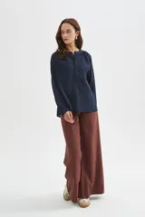 Blusa azul marino de viscosa, con cuello mao, escote con botones y frunces. Presenta mangas largas holgadas y detalles bordados al tono en el frente.