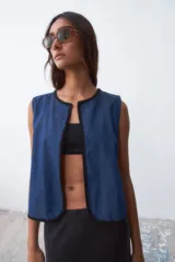 Chaleco azul de denim con ribete negro.