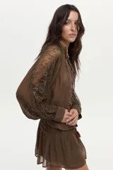 Falda corta vaporosa color marrón, con trabajo de punto smock elástico en la cintura, detalle de canutillos bordados y forro interior.